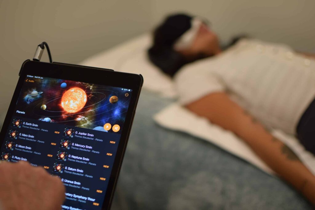 Person lying on the Entle bed during a session, with an iPad nearby displaying the Entle program interface
